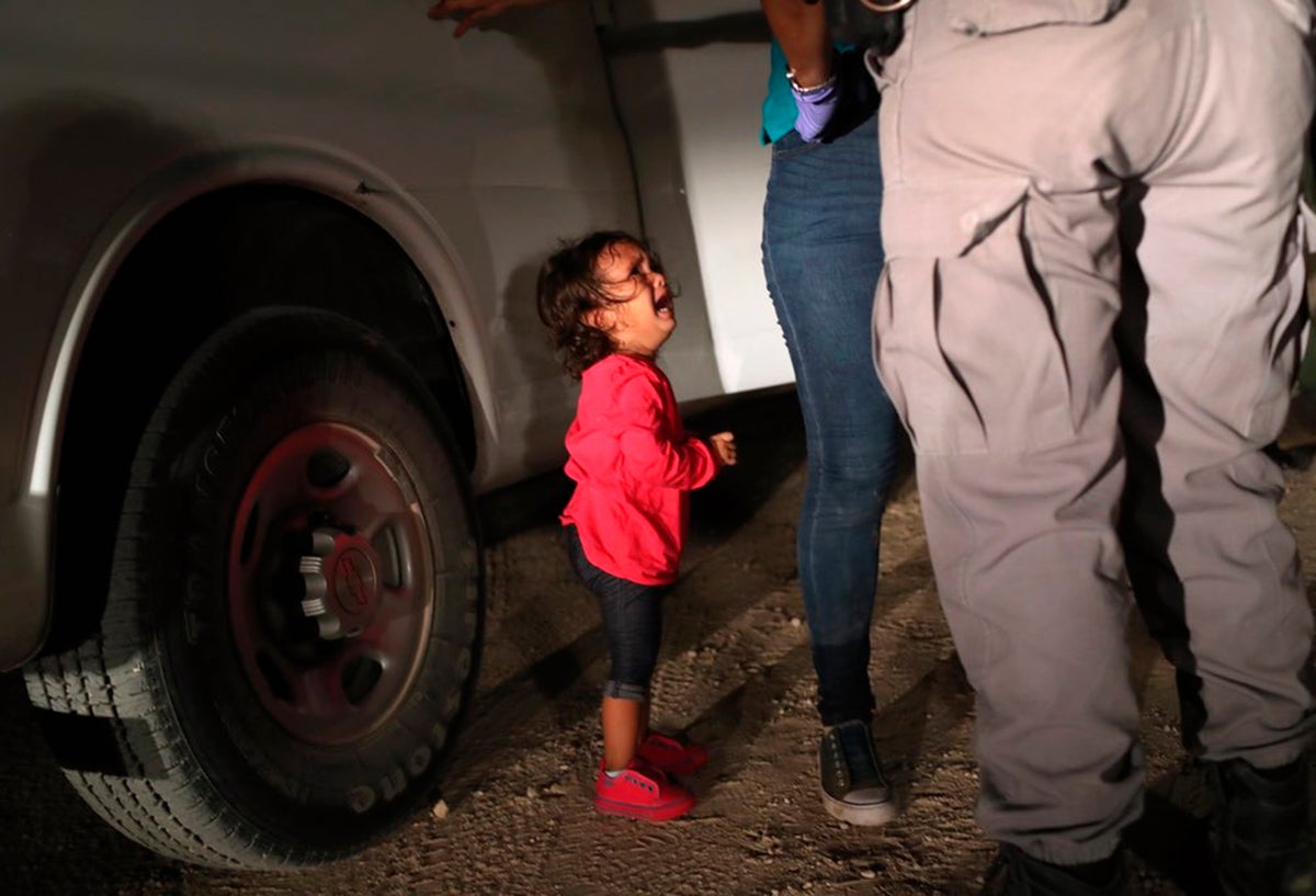 Una niña mirando a un oficial estadounidense tras ser separada de su familia en la frontera
