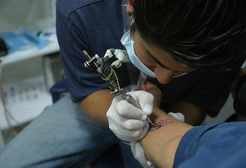 Un tatuador con unos de sus clientes, en Bogotá