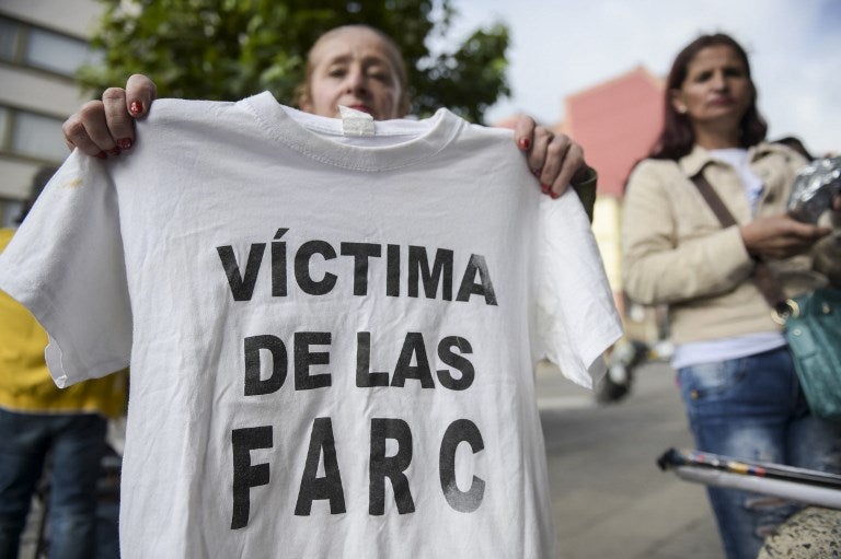 Una mujer sostiene una camiseta con la leyenda "Víctima de las Farc" durante una protesta afuera en la sede de la Jurisdicción Especial para la Paz (JEP) en Bogotá, el 13 de julio de 2018.