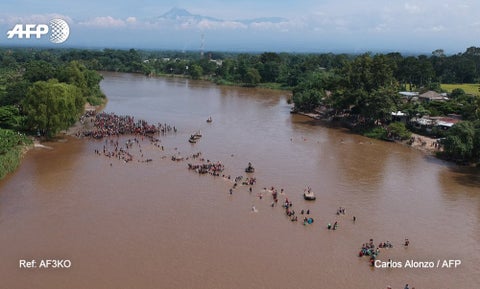 La caravana de migrantes cruza a pie el río que separa Guatemala de México.