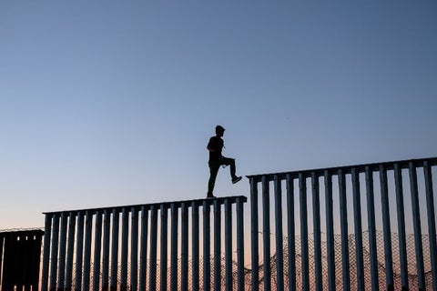 Migrantes en el muro entre México y Estados Unidos