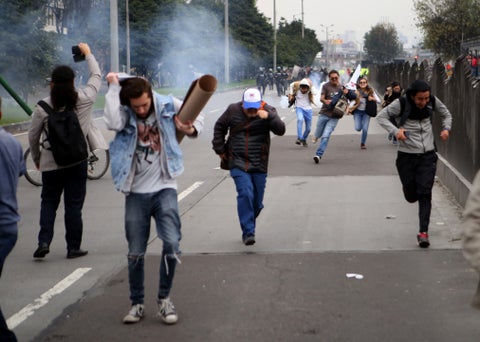 Varios estudiantes escapan de las bombas de aturdimiento del ESMAD