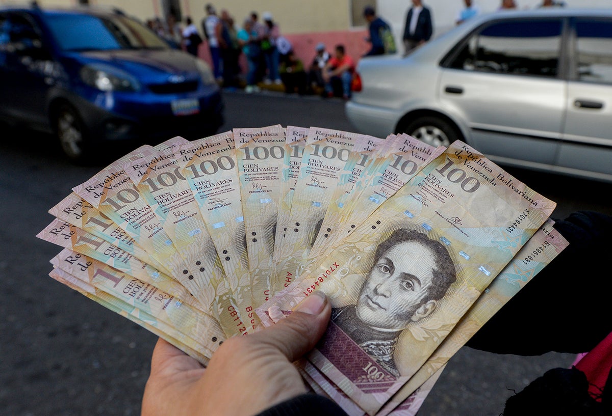 Un ciudadano venezolano expone bolívares, moneda oficial, en las calles de Caracas