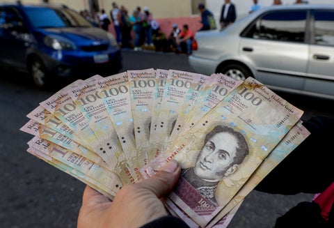 Un ciudadano venezolano expone bolívares, moneda oficial, en las calles de Caracas