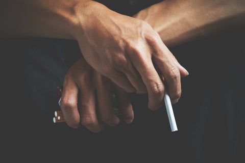 Un hombre sostiene cigarrillos en sus manos