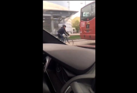 Biciusuario detrás de un articulado de Transmilenio