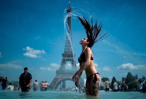 Una mujer se refresca en la fuente de la Plaza del Trocadero, en París, este 25 de junio de 2019, con la Torre Eiffel en el fondo