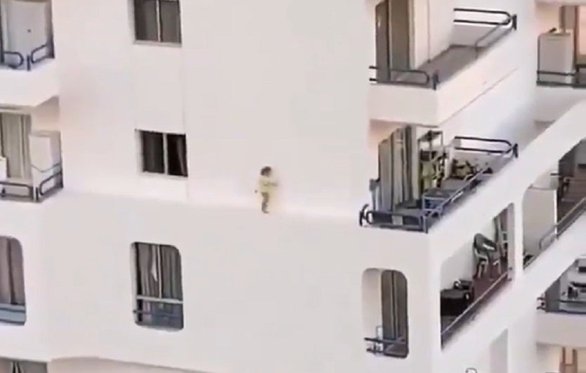 Niña caminando por el estrecho borde de un edificio