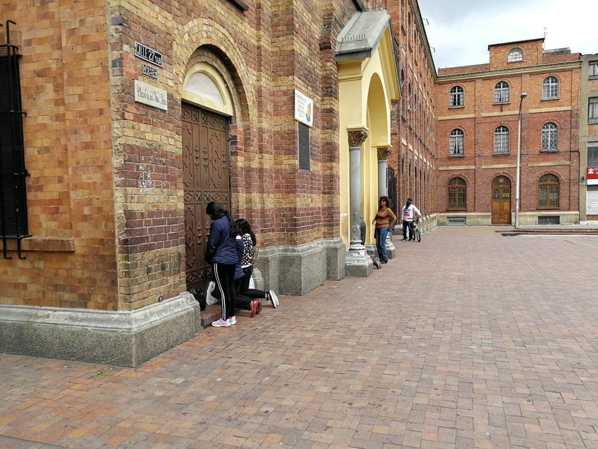 Fieles arrodillados ante las puertas cerradas de la Iglesia del 20 de julio
