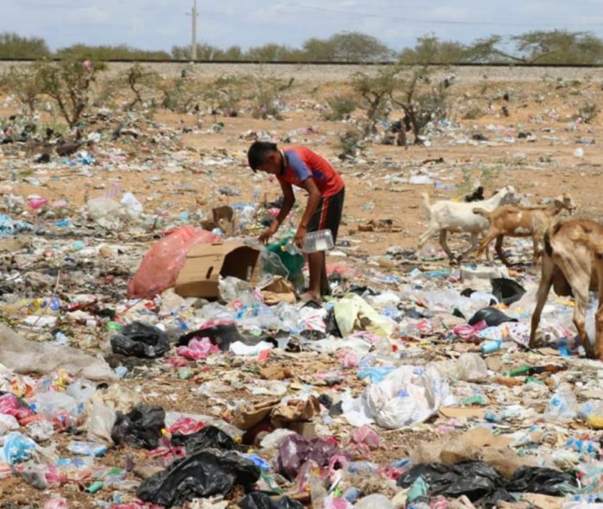 Niño indígena buscando alimentos entre la basura.