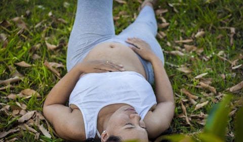 Mujer embarazada recostada en el pasto