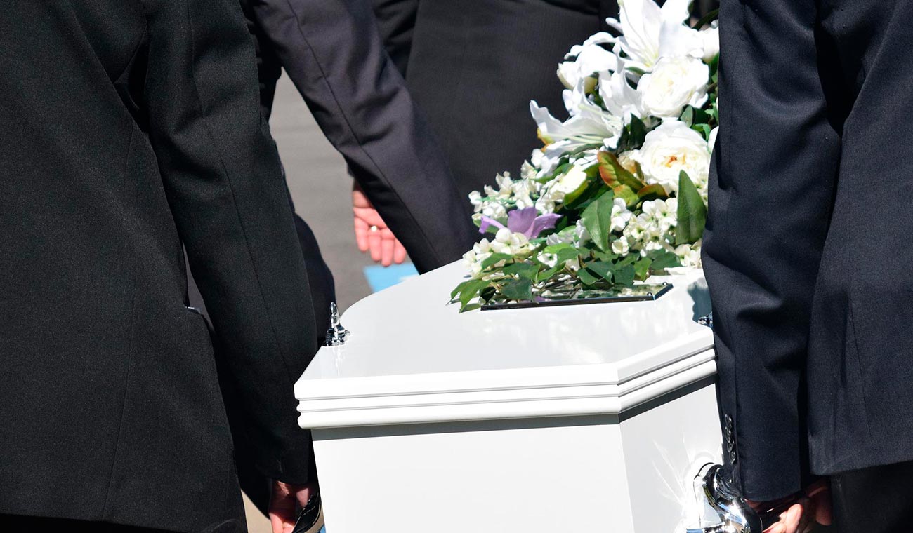 Asistentes a funeral cargan ataúd