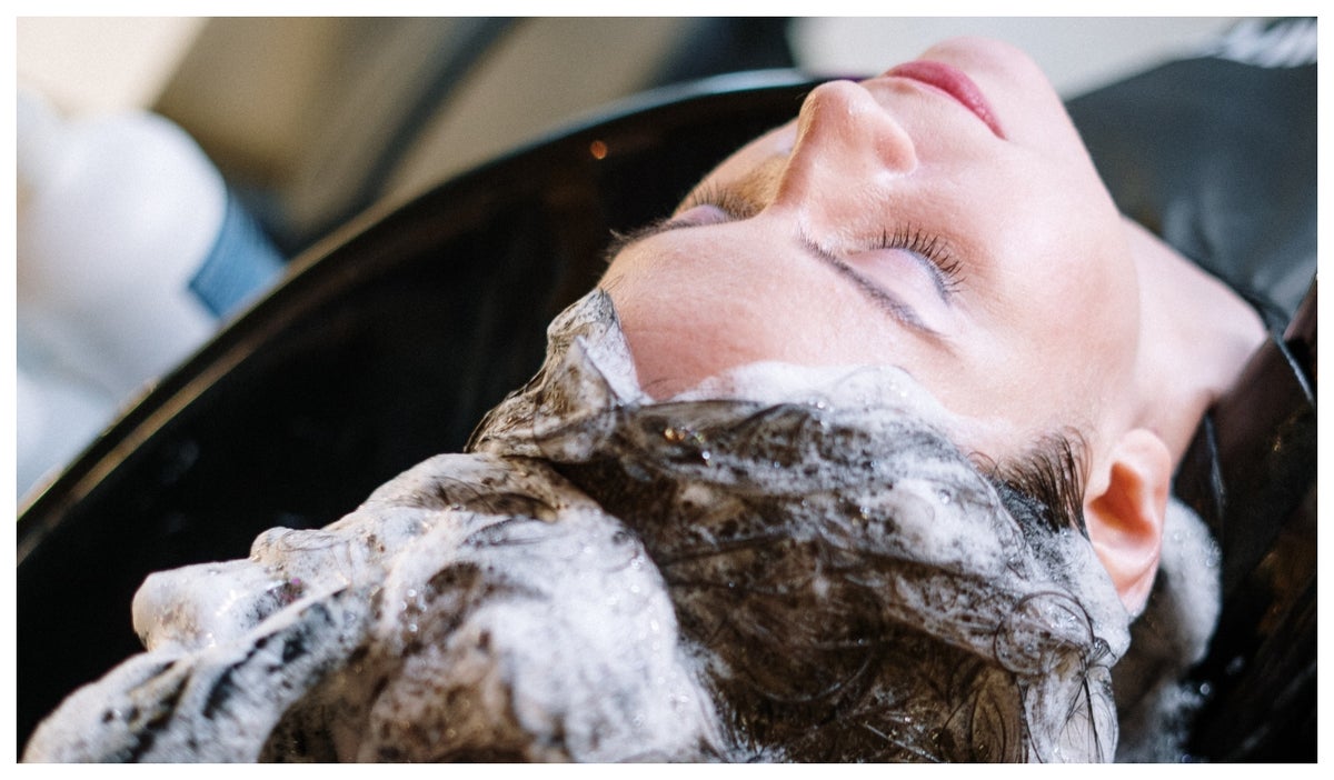 Mujer lavándose el cabello con shampoo