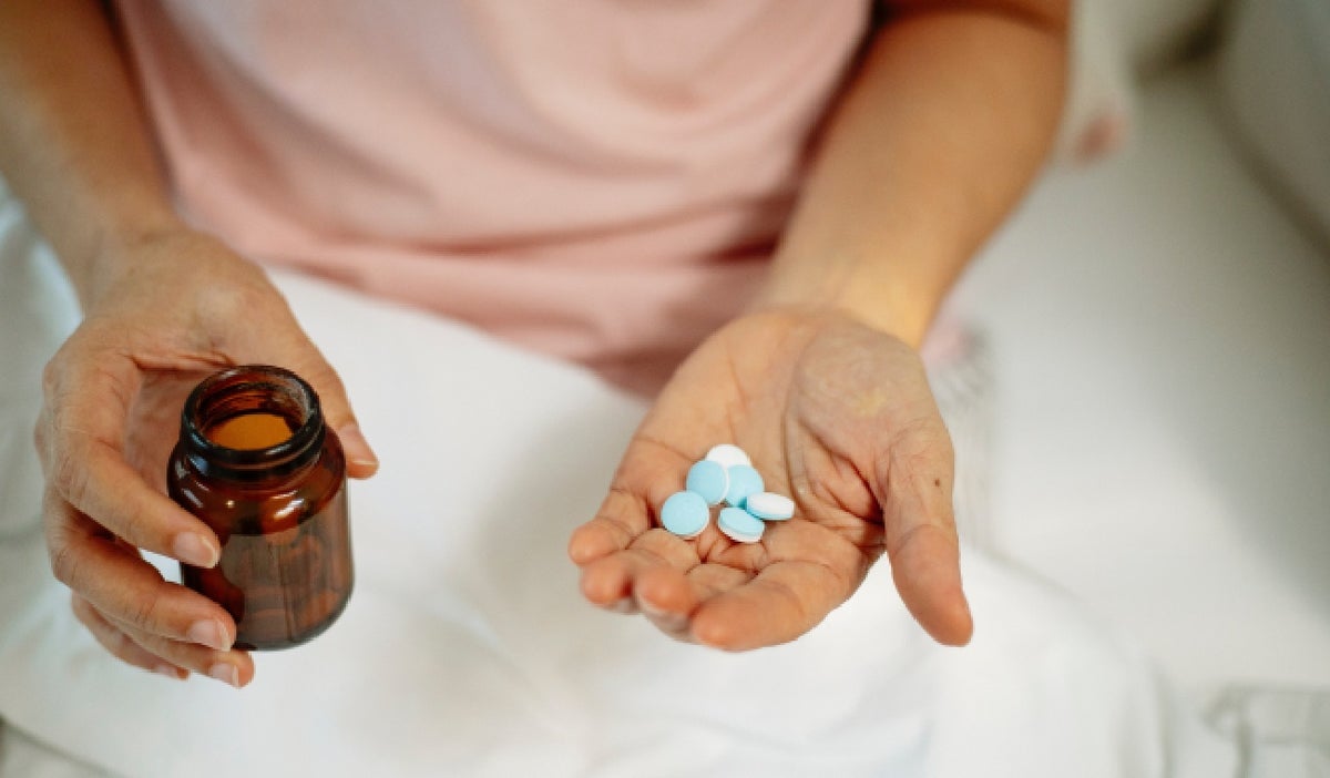 Una mujer con medicinas y un vaso de agua.