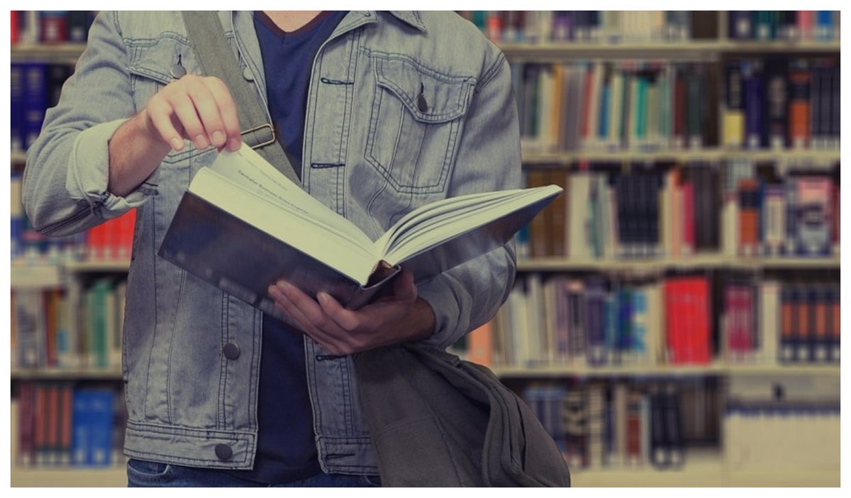 Joven con un libro en la biblioteca