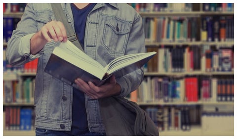 Joven con un libro en la biblioteca