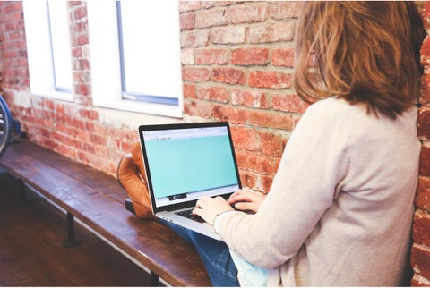 Mujer sentada y en sus piernas tiene un computador