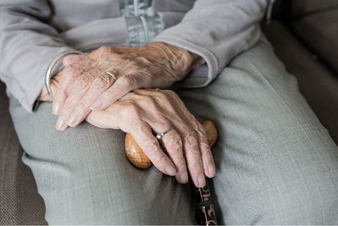 Manos de un anciano cruzadas y con un bastón