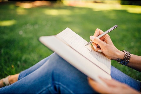 Mujer sentada escribiendo en el aire libre