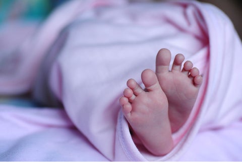 Pies de un bebé recién nacido envuelto en una cobija de color rosa
