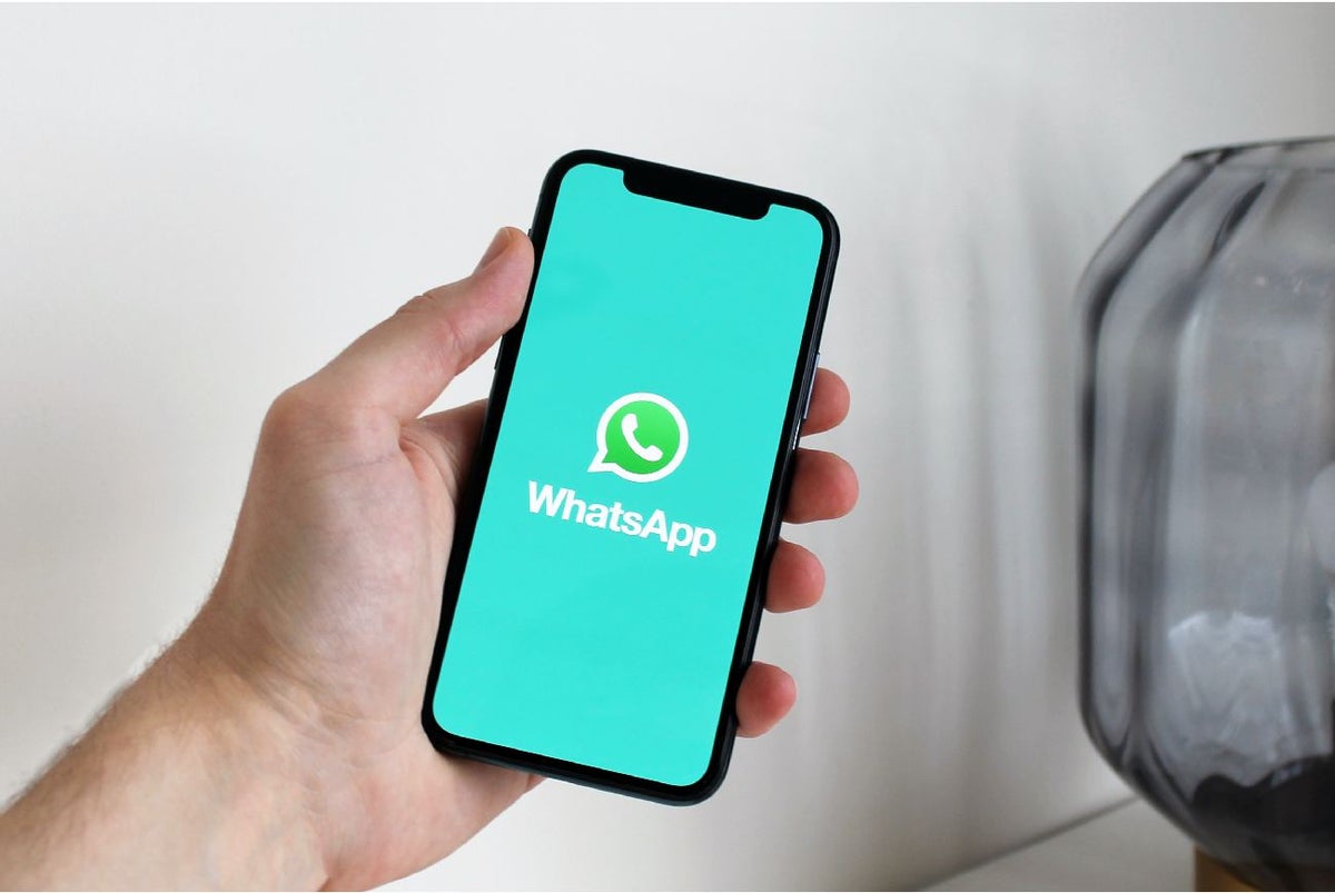Persona con un celular en la mano y abriendo WhatsApp