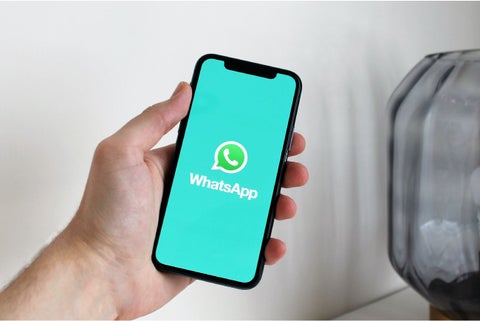 Persona con un celular en la mano y abriendo WhatsApp