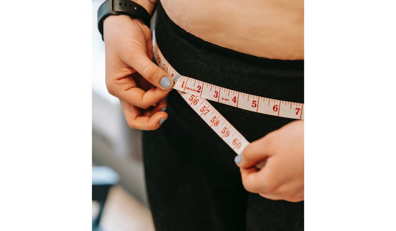 Persona midiendo sus caderas: por qué es malo comer frente a las pantallas