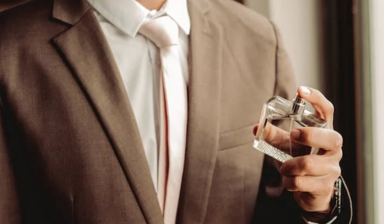Hombre aplicándose perfume