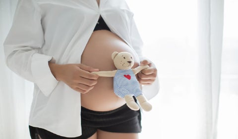 Foto de una embarazada con un peluche en la barriga
