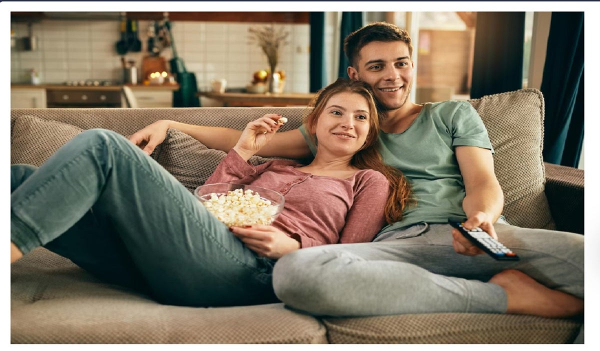 Pareja viendo una película en un sofá y con palomitas
