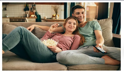 Pareja viendo una película en un sofá y con palomitas