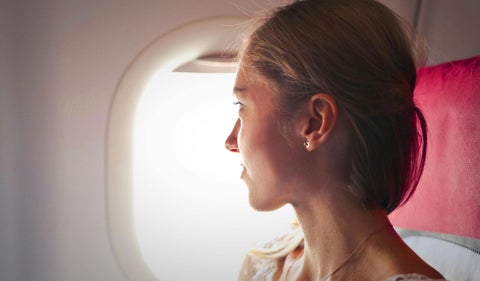 Mujer mirando por la ventanilla de un avión