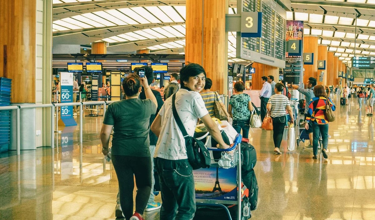 Joven con maletas y de fondo un aeropuerto