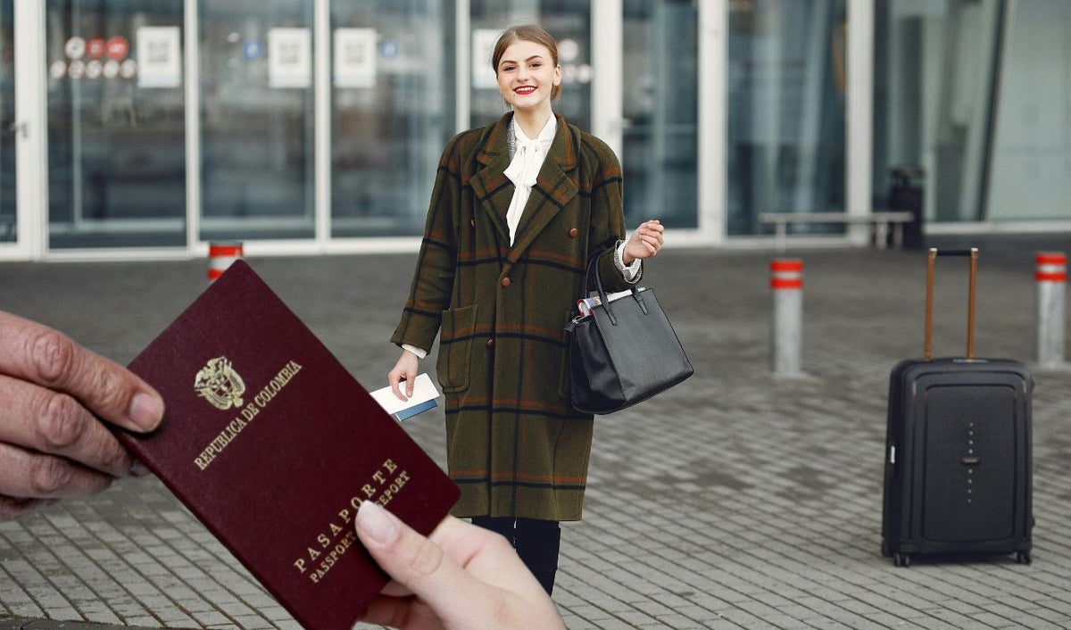 Mujer con maleta de viaje y pasaporte colombiano
