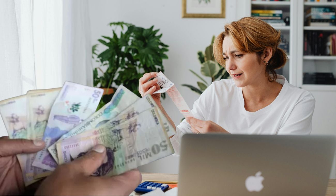 Una mujer haciendo cuentas y dinero colombiano