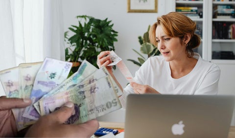 Una mujer haciendo cuentas y dinero colombiano