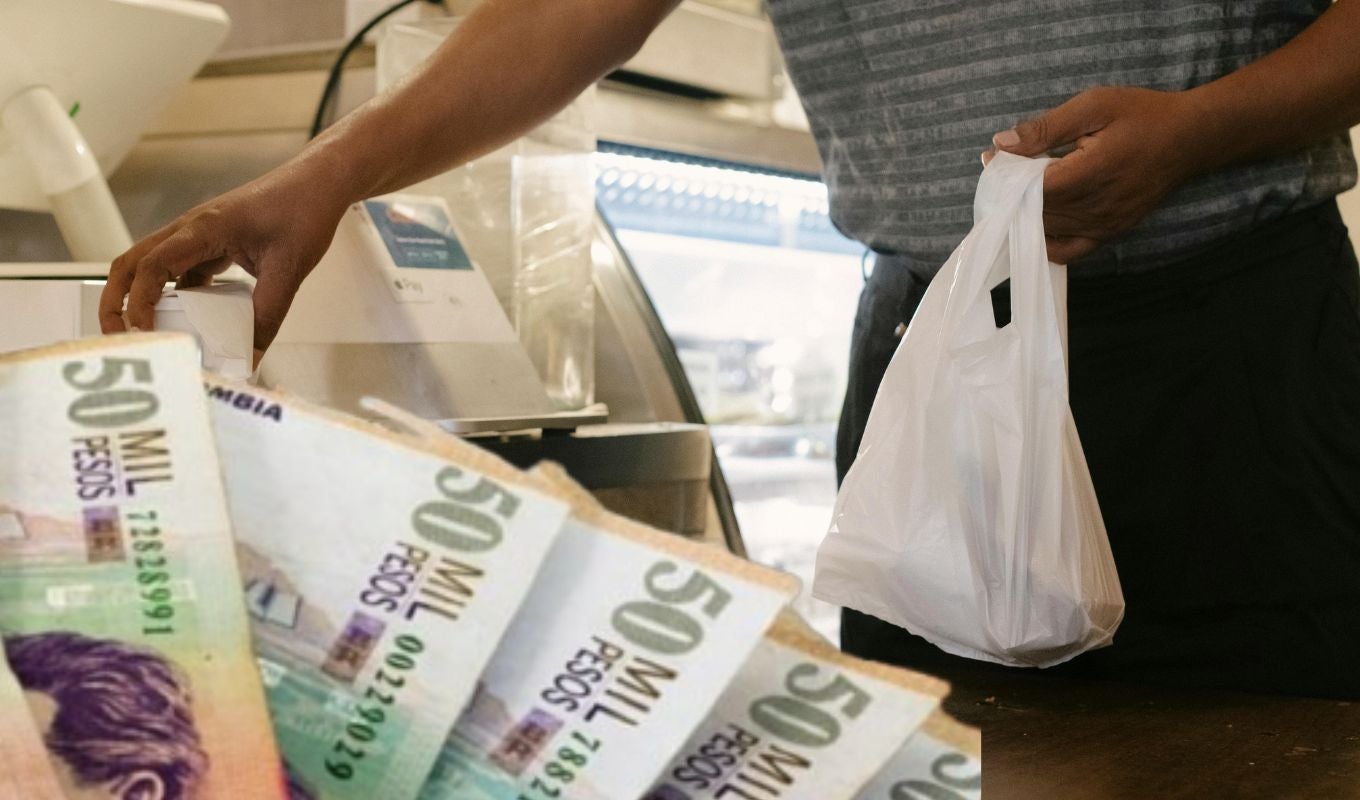Persona con bolsas de plástico y billetes colombianos