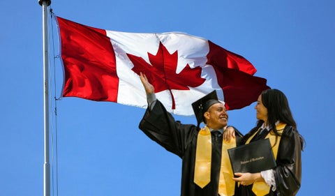 Bandera de Canadá y dos personas graduadas de la universidad