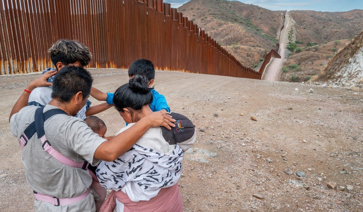 Una familia migrante que busca asilo desde Ecuador reza al lado de la frontera