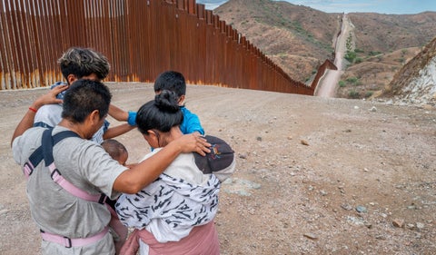 Una familia migrante que busca asilo desde Ecuador reza al lado de la frontera