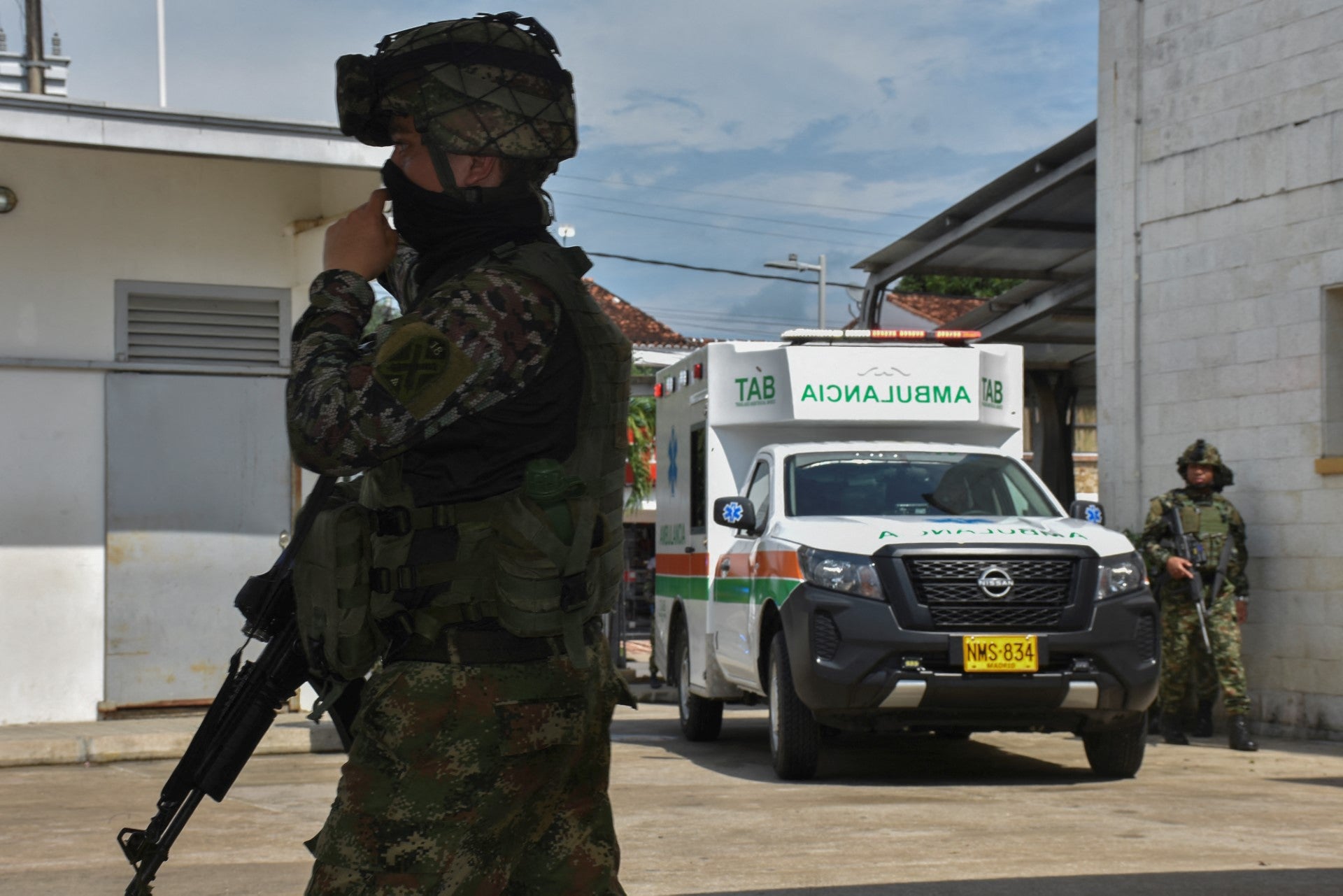 Un soldado hace guardia en Arauca mientras al fondo se ve una ambulancia que transporta a otro militar herido.