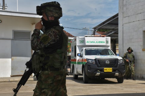Un soldado hace guardia en Arauca mientras al fondo se ve una ambulancia que transporta a otro militar herido.