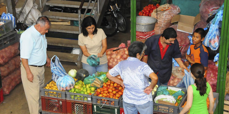 Consumidores en un mercado comprando productos básicos de la canasta familiar