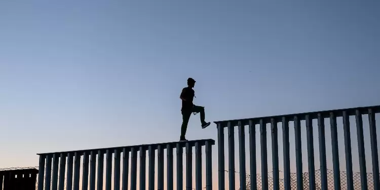 Migrantes en el muro entre México y Estados Unidos