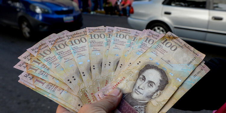 Un ciudadano venezolano expone bolívares, moneda oficial, en las calles de Caracas