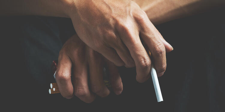 Un hombre sostiene cigarrillos en sus manos