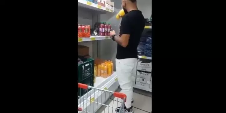 Hombre tomando de varias botellas de jugo en una tienda D1.