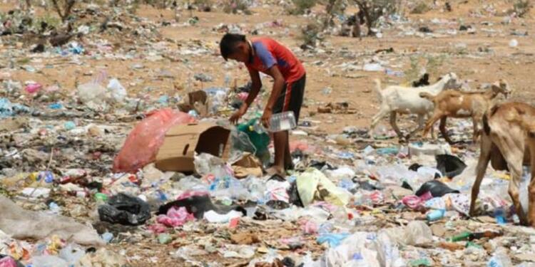 Niño indígena buscando alimentos entre la basura.