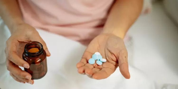 Una mujer con medicinas y un vaso de agua.