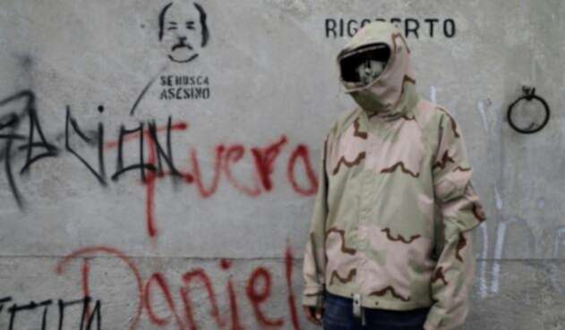 Un estudiante posa al lado de un grafiti en el que se lee "Fuera Daniel" en alusión al presidente Ortega.